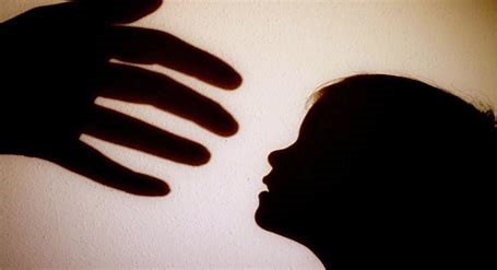 Image of an adult hand reaching towards a child's face looking up. 